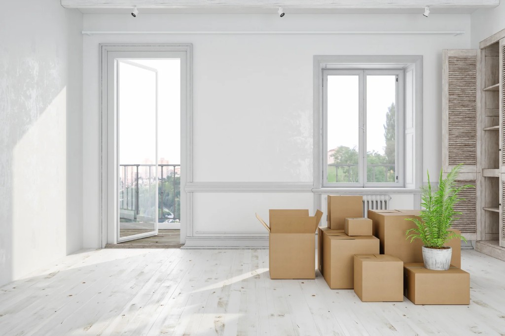 Empty bright apartment with moving boxes stacked in the center of the room